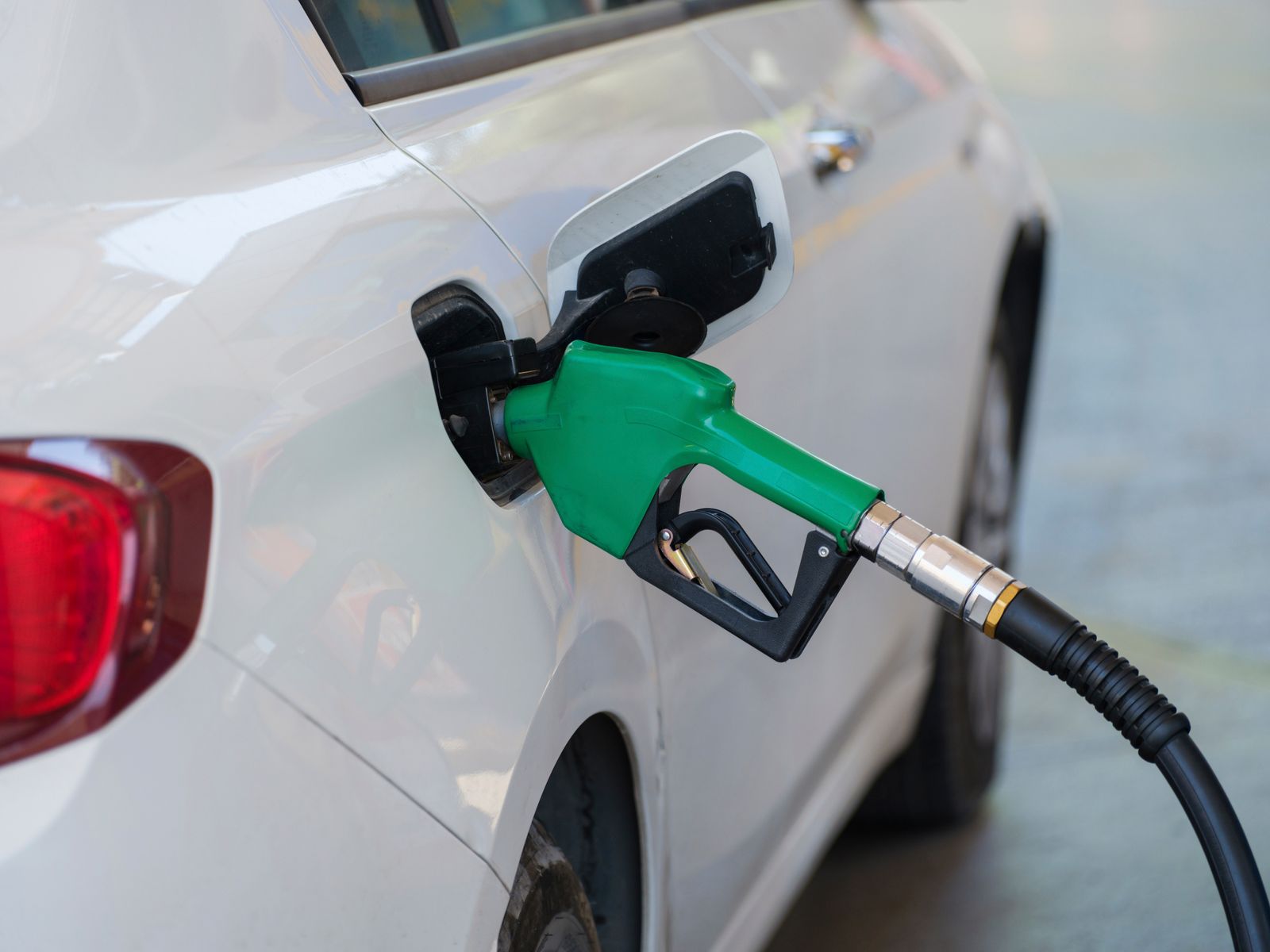 Zapfpistole beim Betanken eines Autos als Symbol für Kraftstoffkosten und Energiesteuer.